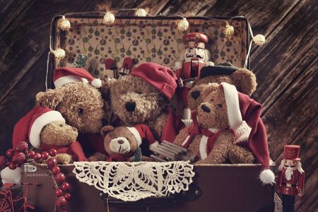 old suitcase full of teddy bears in Santa caps ready for Christmasの写真素材