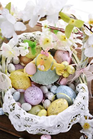 easter decoration with funny hen figurine in wicker basket full of colorful eggs