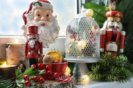 Christmas decoration on the windowsill with nutcracers, Santa Claus and candle lantern