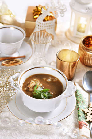 traditional Christmas Eve mushroom soup with barley on festive table in white and golden colorsの写真素材