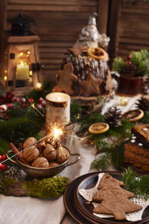 Christmas table decoration with traditional pastries and walnuts in rustic style with sparklers fireworksの写真素材