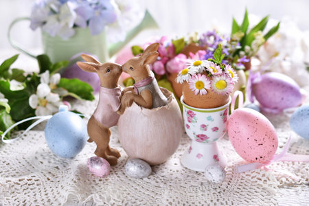 Easter decoration with funny kissing bunnies figurine and spring flowers in egg shells on festive...