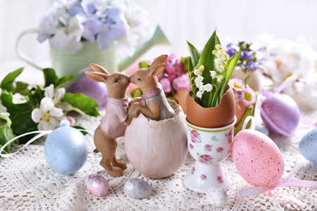 Easter decoration with funny kissing bunnies figurine and spring flowers in egg shells on festive...