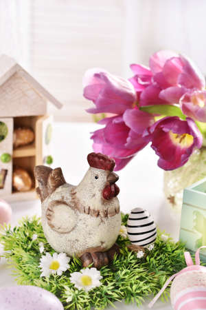 Easter table decoration with hen figurine and bunch of purple tulipsの写真素材