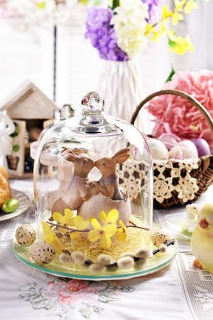Easter table decoration with kissing bunnies in glass cloche