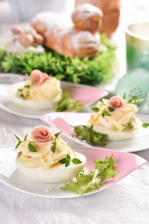 eggs with mayonnaise stuffed with vegetable salad with prosciutto ham decoration on Easter table