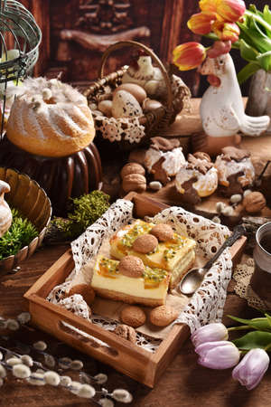 Traditional Easter pastries- cheesecake with passion fruit, ring cake and muffins on festive table...