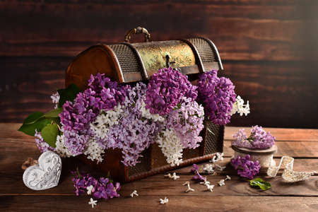 beautiful bunch of 3 color lilac in old wooden chest on the table in rustic styleの写真素材