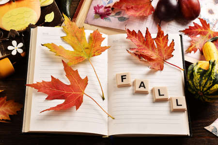 Fall background with opened diary notebook with colorful leaves and seasonal decors on wooden table