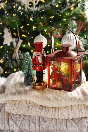 Christmas still life with a nutcracker and candle lantern on winter sweaters in front of Christmas treeの写真素材