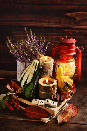 Autumn still life with ornamental gourds, candles, heather flowers and oil lamp in rustic styleの写真素材