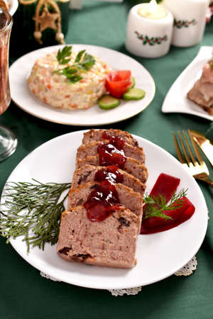 Sliced cranberry pate on white plate and other traditional Christmas Eve dishes on festive tableの写真素材