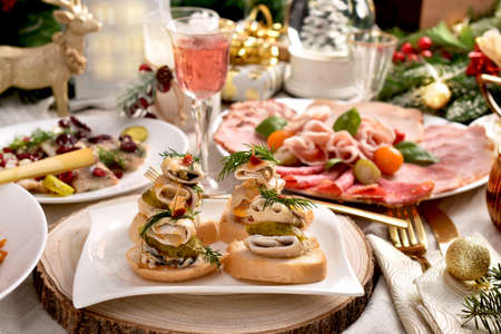 Herring and pickle rolls as mini sandwiches and other appetizers on Christmas tableの写真素材
