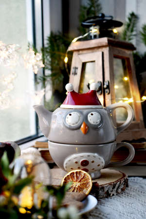 Owl shaped teapot, wooden candle lantern and Christmas decors on window sillの写真素材