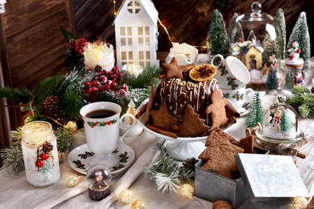 Gingerbread cookies in metal box and ring cake with chocolate glaze on festive table in vintage style for Christmasの写真素材