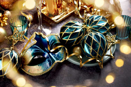 Carnival party decorations with venetian mask and ornaments in turquoise and golden colors on the tableの写真素材