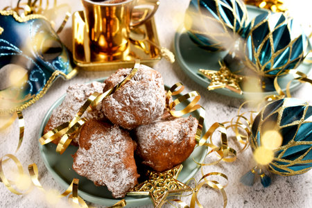 A plate of homemade donuts and a cup of coffee on carnival party table with venetian mask and ornaments in blue and golden colorsの写真素材