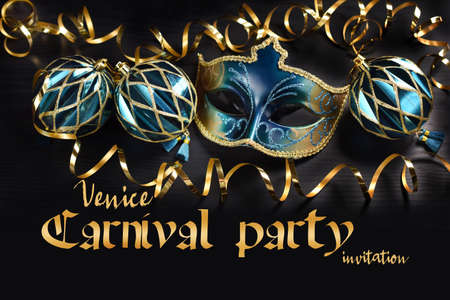 Carnival party invitation with venetian mask and ornaments in turquoise and golden colors with inscription on black backgroundの写真素材