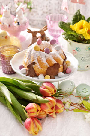 Easter ring cake with egg shaped candies and sprinkled with powdered sugar on festive table
