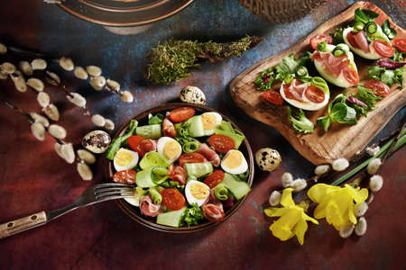 Easter breakfast with fresh vegetable salad with prosciutto ham, quail eggs, cucumber, avocado and...