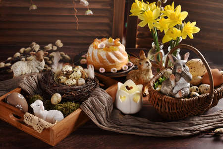 Easter table decorations, flowers and ring cake with raisins in rustic styleの写真素材