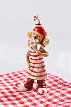 A clown figurine in red and white clothes standing on checkered napkinの写真素材
