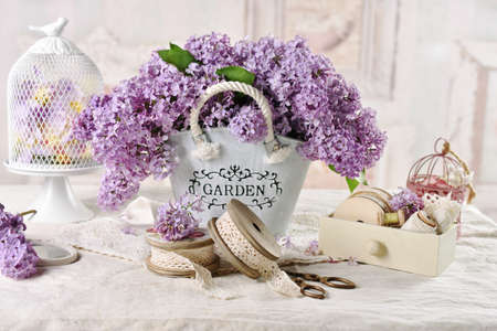 Beautiful composition with bouquet of purple lilac blossoms in metal bucket in shabby chic style interiorの写真素材