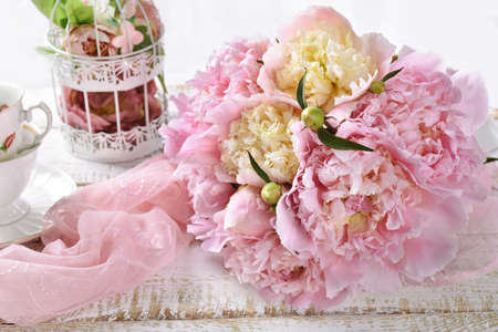 Bunch of pink and yellow peonies lying on white wooden tableの写真素材