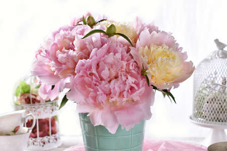 Bouquet of pink and yellow peonies in mint color vase standing on the tableの写真素材