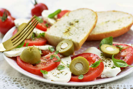 Fresh caprese salad with mozzarella, tomatoes, green olives and thyme with basil leavesの写真素材