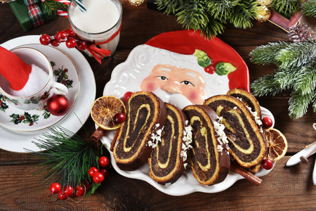 Top view of Christmas table with sliced poppy cake on Santa Claus shaped plate and a glass of milkの写真素材