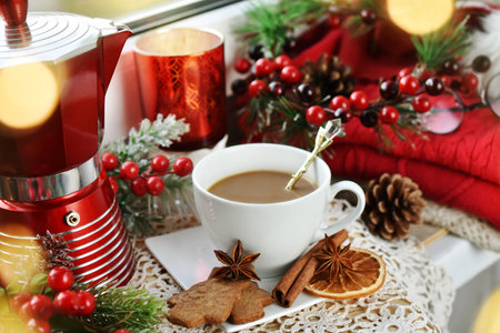 A cup of coffee and gingerbread cookies on windowsill with Christmas decorationsの写真素材