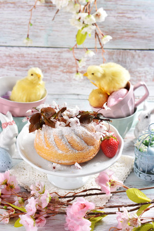 <p>Easter table with homemade ring cake sprinkled with powdered sugar, spring decorations in pastel colors</p>の写真素材