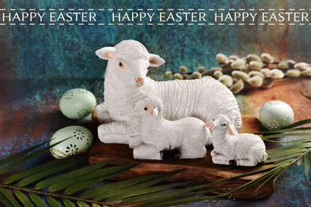 Easter card with a sheep cly figurine with two lambs lying on grunge background, eggs and Easter palm wish wishes textの写真素材