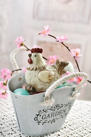 Easter table decoration with a hen figurine and colorful eggs in metal basket in vintage styleの写真素材