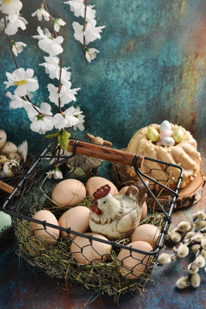 Vintage style Easter table with eggs and a hen figurine in wire basket and ring cake on grunge backgroundの写真素材