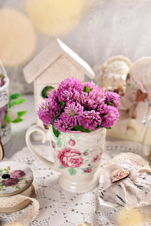 Bunch of red clover flowers in a cup on vintage style tableの写真素材