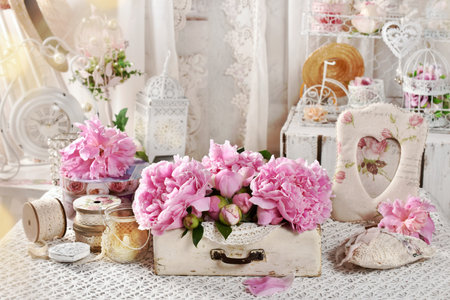 Pink fresh peonies in old wooden drawer on the table in shabby chic style interior with many decorsの写真素材