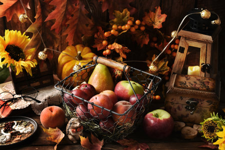 Vintage style autumn still life with seasonal fruits in wire basket on dark wooden table with decorsの写真素材