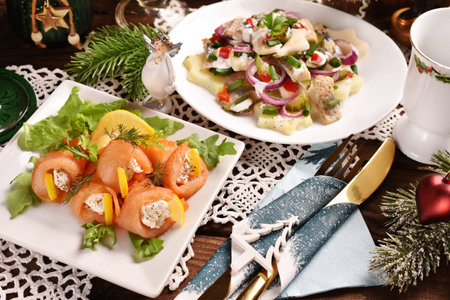Smoked salmon rolls stuffed with cream cheese and herring salad on Christmas table in rustic style.の写真素材