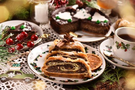 Christmas pastries with poppy seed roll in puff pastry and poppy chocolate cake on festive table in rustic styleの写真素材