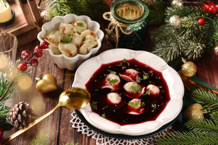 Traditional red borscht with dumplings filled with mushrooms and sauerkraut for Christmas Eve's supper on festive table in rustic styleの写真素材