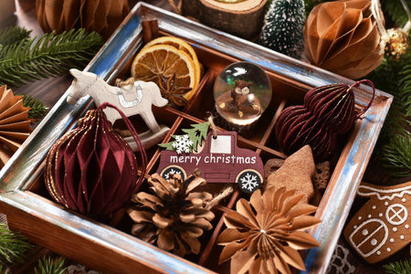 Christmas decors with car shaped ornament, handmade paper ones, rocking horse and others in old wooden shadow box lying on the tableの写真素材