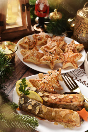 Fried carp with almond flakes and star shaped puff pastry pies filled with mushrooms for Christmas Eve's super in Polandの写真素材