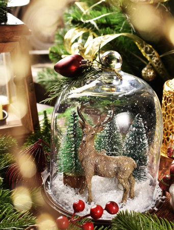 Vintage style Christmas table decoration with realistic deer figurine and trees inside the glass cloche with falling snowの写真素材