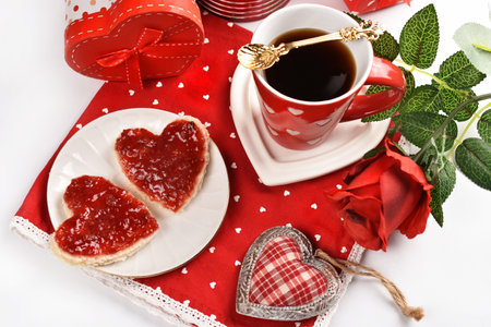 Valentine's coffee and heart shaped toasts with raspberry jam on the table with red napkinの写真素材