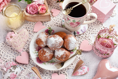 Top view with mini donuts sprinkled with powdered sugar and a cup of coffee with romantic decors for Valentine's partyの写真素材
