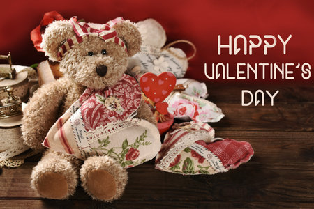 Valentine's background in vintage style with cute teddy bear toy holding a handmade textile heart and greeting textの写真素材