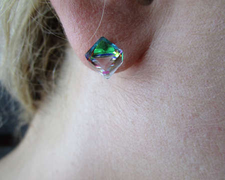 Blonde woman with a multicolored earring on her ear.の写真素材