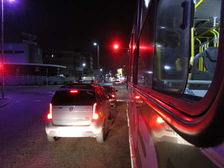 Avenue with stopped vehicles, waiting for the traffic light that is red, to open, and whose color is reflected in the stopped vehicles.の写真素材